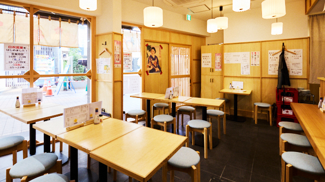 木のテーブルと椅子が並ぶ、さくらがわの明るい店内